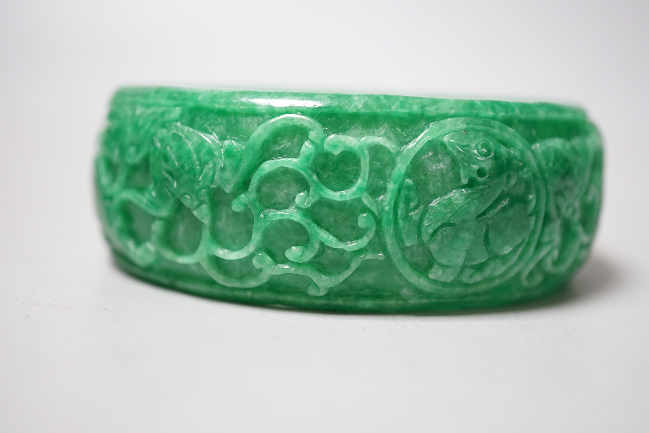 A Chinese carved jadeite bangle, 8.5cm diameter